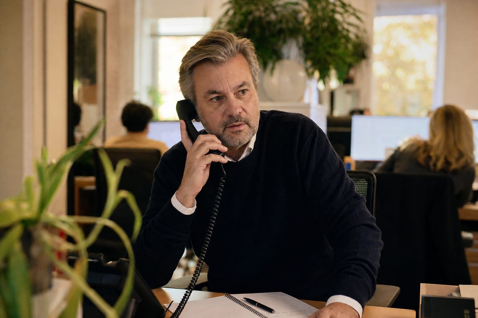Recruiter im Büro am Telefon, daneben Notizblock und Tischapparat